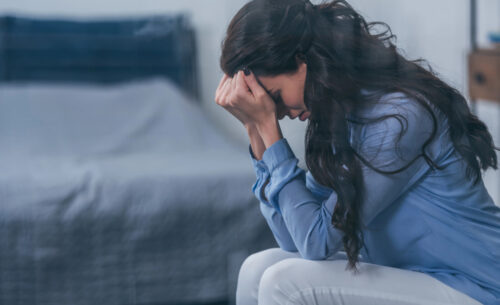 Woman with head in her hands appearing upset. Credit: Andrew Lozovyi