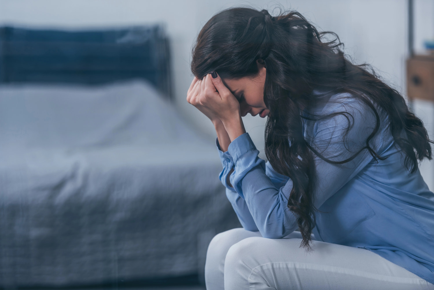 Woman with head in her hands appearing upset. Credit: Andrew Lozovyi