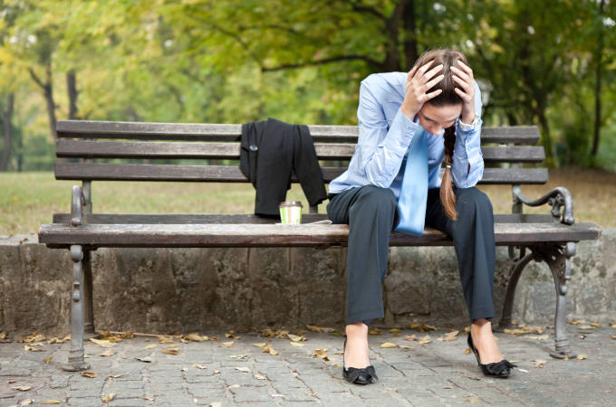 worried businesswoman sitting on bench in park